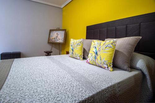 a bedroom with a large bed with yellow walls at El Palomarcico in Zamora