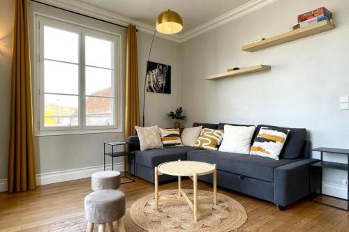 ein Wohnzimmer mit einem blauen Sofa und einem Tisch in der Unterkunft Suites Rive Gauche - Région Fontainebleau - Chez Victor in Melun