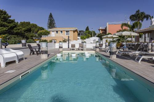 a swimming pool with chairs and tables and a building at Small Luxury apartments Pool and sea view - Stella Del Mare in Fontane Bianche
