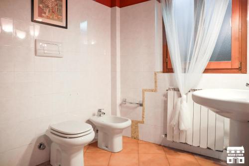 bagno bianco con servizi igienici e lavandino di THE LOFT by Design Studio a Bellano