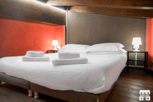 una camera da letto con un grande letto con lenzuola e cuscini bianchi di THE LOFT by Design Studio a Bellano