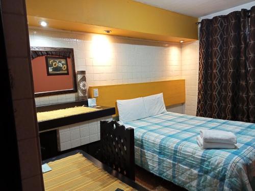 a small bedroom with a bed and a mirror at Hotel Posada El Gran Cipres in San Cristóbal de Las Casas