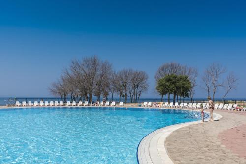 a person walking around a large swimming pool at Apartments Polynesia Plava Laguna in Umag