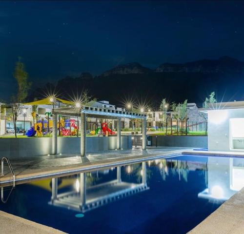 una piscina con un parque infantil al fondo por la noche en Family Home Apodaca, en Monterrey
