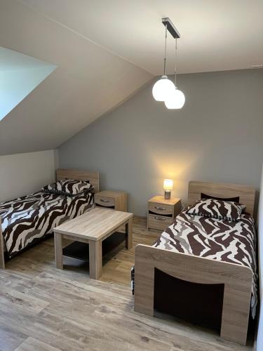 a attic room with two beds and a table at Andrzejówka in Cieplice