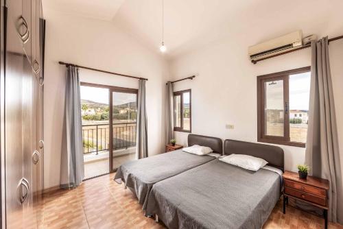ein Schlafzimmer mit einem großen Bett und einem Balkon in der Unterkunft Villa Pella in Peyia