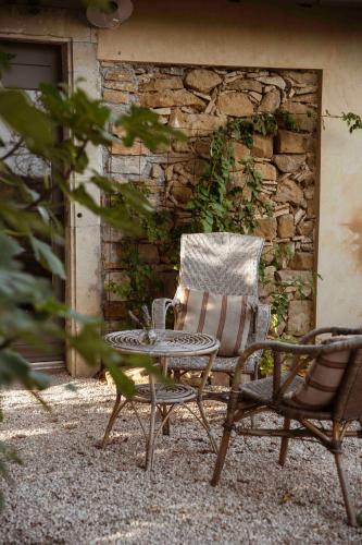 une table et une chaise assises à côté d'un mur en pierre dans l'établissement Maison Bellamant, à Alan