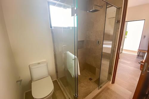 Un baño con inodoro y ducha de cristal. en BEAUTIFUL SUIT WITH INFINITY POOL AND GYM IN THE MIDDLE OF THE JUNGLe and grill, en Tulum
