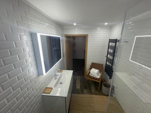 une salle de bain avec un lavabo, un miroir et une chaise dans l'établissement Appartement centre-ville d'Evian les Bains, à Évian-les-Bains