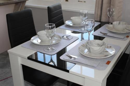 a white dining table with glasses and plates on it at Spacious 2-Bed 2-Bath Apartment with Free Parking - Central Poole in Poole