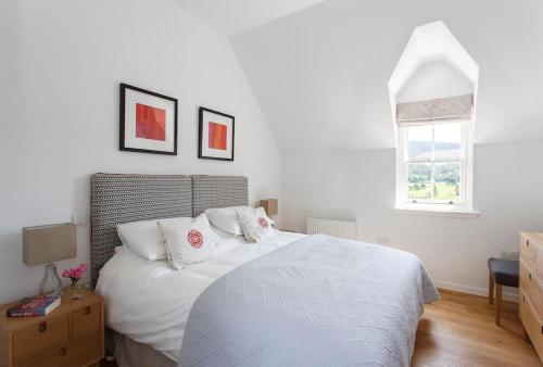 een slaapkamer met een wit bed met witte lakens en een raam bij Stalker's Lodge in Perth