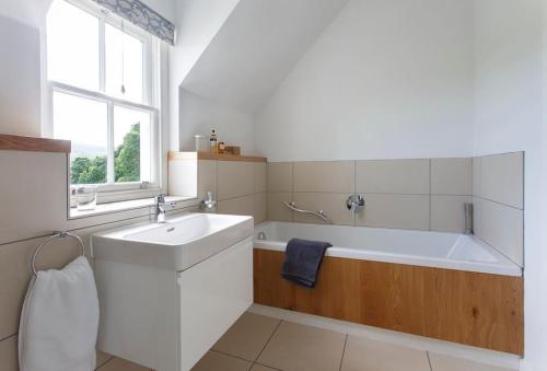 een witte badkamer met een bad en een wastafel bij Stalker's Lodge in Perth