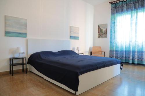 Un dormitorio con una cama con una manta azul. en Ampio bilocale in centro con parcheggio gratuito nella proprietà, vicino a stazione Como-Milano, en Erba