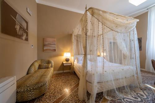 a bedroom with a canopy bed and a chair at Lungarno Buozzi 7 Apartments in Pisa
