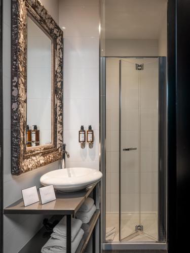une salle de bain avec un lavabo et un miroir dans l'établissement Grand Hotel Lafayette, à Paris
