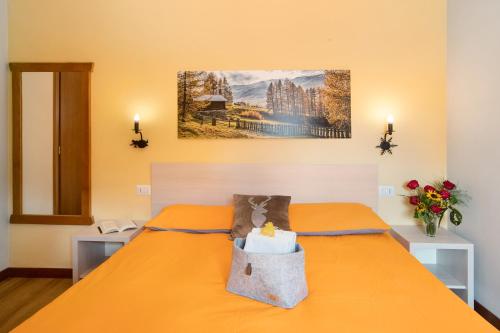 Mountain Apartments Livigno في ليفينو: غرفة نوم مع سرير برتقالي مع حقيبة عليه