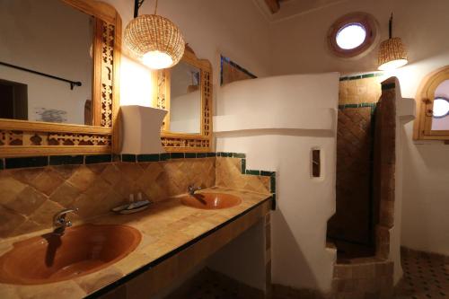 a bathroom with two sinks and two mirrors at Dar Jnan Tiouira Dades in Tamellalt