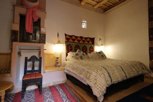 a bedroom with a large bed and a chair at Dar Jnan Tiouira Dades in Tamellalt