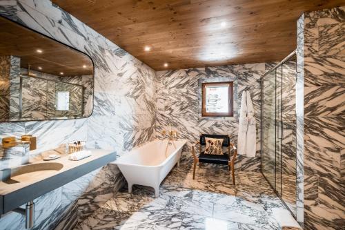 y baño con bañera y lavamanos. en Hôtel LA MOURRA en Val dʼIsère
