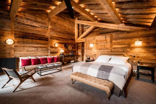 1 dormitorio en una cabaña de madera con 1 cama y 1 sofá en Hôtel LA MOURRA, en Val dʼIsère