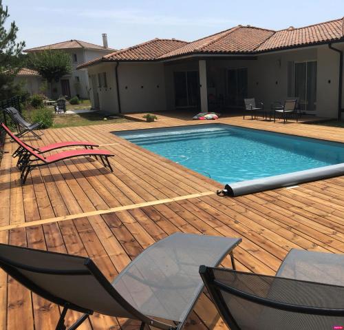 una piscina su una terrazza in legno con 2 sedie di Villa Donosti Chambres d'Hôtes a Lanton