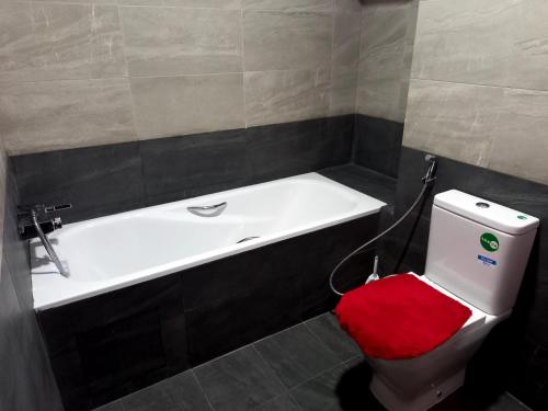 La salle de bains est pourvue d'une baignoire et de toilettes avec un siège rouge. dans l'établissement Luxe Bord de Mer Appart Prestige, à Agadir
