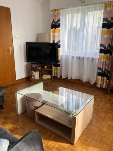 a living room with a glass coffee table and a tv at Townhouse - Strasbourg Robertsau in Strasbourg