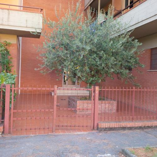 una recinzione rossa con un albero di fronte a un edificio di Casa Venturi a Scandicci