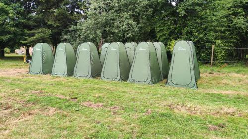 een rij groene tenten in een grasveld bij Camping Vieilles Charrues Petit-déjeuner navette et priscine inclus dans le prix proche Carhaix 