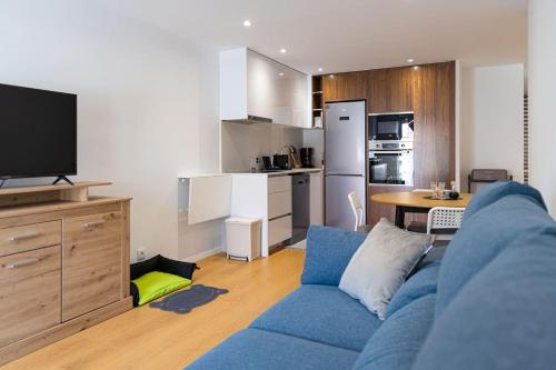 ein Wohnzimmer mit einem blauen Sofa und einer Küche in der Unterkunft Charming Beach Retreat by MP in Madalena