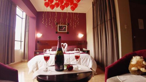 um quarto com uma mesa com duas garrafas e taças de vinho em HOTEL LAS TERRAZAS INN em Andahuaylas