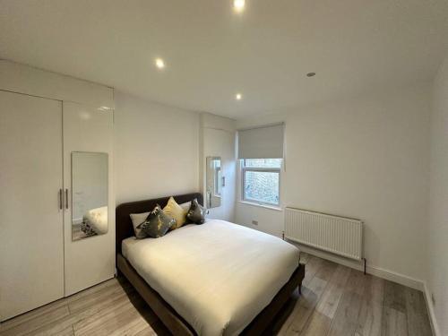 a bedroom with a large white bed and a window at 3 bed Hackney/Harringay Flat in London