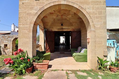 einen steinernen Torbogen mit zwei grünen Stühlen und Blumen in der Unterkunft Villa Alida - Con Ampio Giardino E Piscina Privata Nel Salento in Andrano