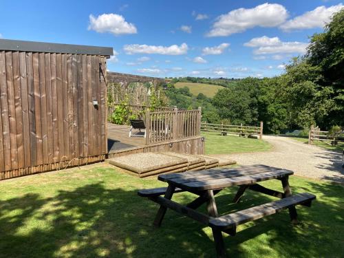 a picnic table and a bench in the grass at Unique Private Lodge in Cornwall sleeps 4 