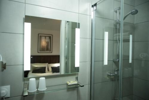 a bathroom with a shower and a mirror at Hôtel du Marché Paris in Paris