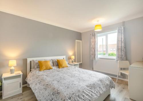 um quarto com uma cama com almofadas amarelas e uma janela em Cornfield Bungalow em Haddiscoe