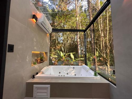 a bath tub in a room with a large window at Cabanas Gariba in Encantado