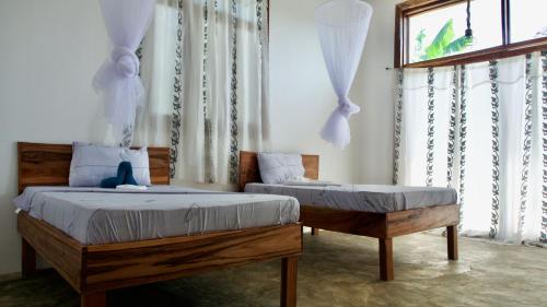 a bedroom with two twin beds and a window at Jaje Paje Villa in Paje
