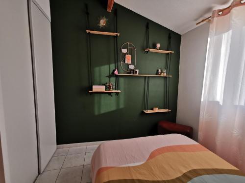 - une chambre dotée d'un mur vert avec des étagères et un lit dans l'établissement Maison Cosy 6 couchages à 700 mètres de la plage, à Torreilles