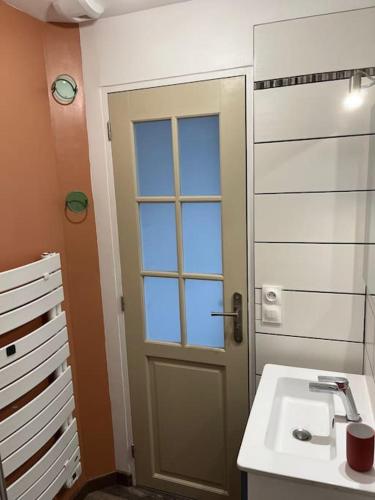 La salle de bains est pourvue d'un lavabo et d'une porte avec fenêtre. dans l'établissement Coquette maison de pêcheur, à Ouistreham