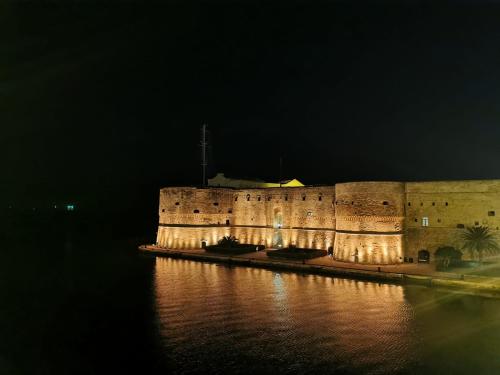 a large stone building with lights on the water at night at Villa la Gravina in Statte