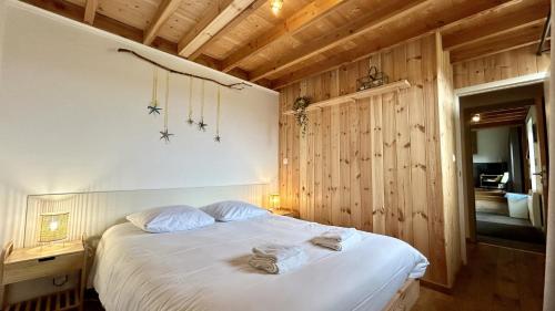 Schlafzimmer mit einem Bett mit weißer Bettwäsche und Holzwänden in der Unterkunft Le 225 villa 8 personnes in Saint-Valery-sur-Somme
