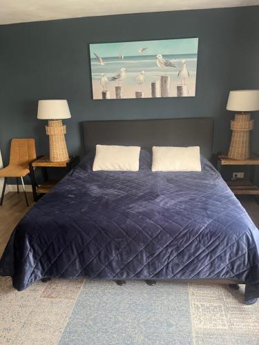 a bed with a blue comforter in a bedroom at B&B De Koog Texel in De Koog