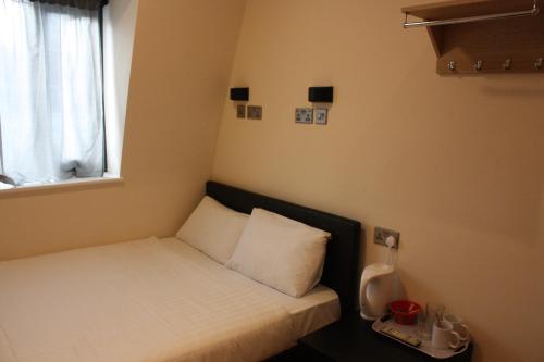 ロンドンにあるホテル オリンピアの窓付きの客室の小さなベッド1台分です。