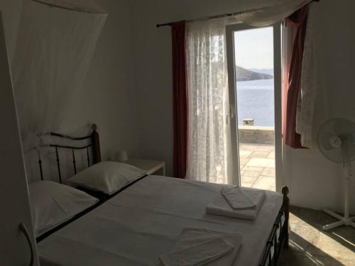 Villa Paloma, Tinos Island في Kardhianí: غرفة نوم بسرير ونافذة كبيرة