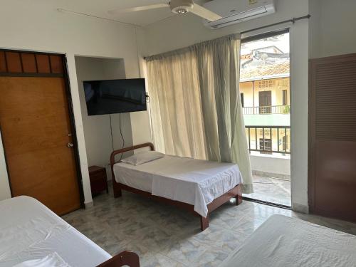 Schlafzimmer mit einem Bett, einem TV und einem Fenster in der Unterkunft Hotel Sandiego in Puerto Berrío