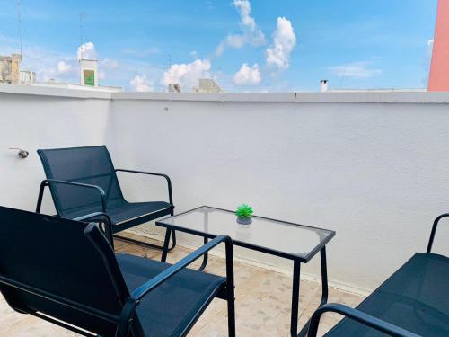 a patio with two chairs and a table and a white wall at Tre Balconi - Casa Vacanza Salento in Carmiano