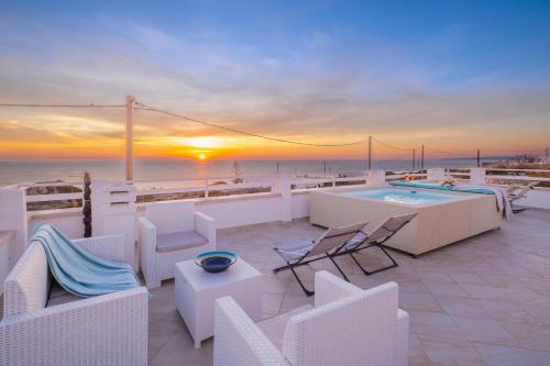 a patio with white chairs and a pool and the ocean at Villa Monteduro - Leuca in Leuca