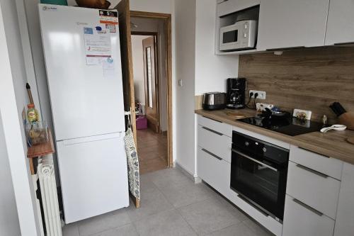 Il comprend une cuisine équipée d'un réfrigérateur blanc et d'une cuisinière. dans l'établissement Bright apartment - near the beach, au Pradet