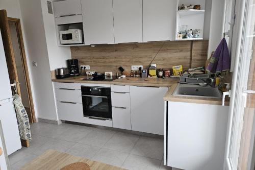 une cuisine avec des armoires blanches et un évier dans l'établissement Bright apartment - near the beach, au Pradet